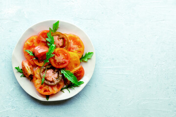 Fresh tomato and rocket salad. A variety of tomatoes of different sorts, shot from above with arugula leaves. Healthy summer food, shot from above with a place for text