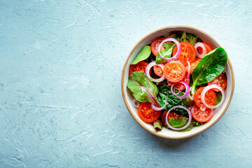 Salad with tomato, fresh leaves, and onions, overhead flat lay shot. Healthy diet, simple vegan...