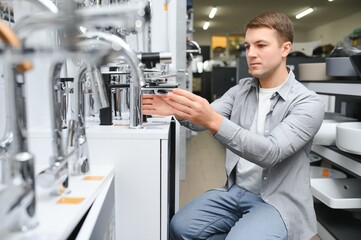 Fototapeta premium man chooses a bathroom faucet in a construction supermarket, plumbing repairs in the house