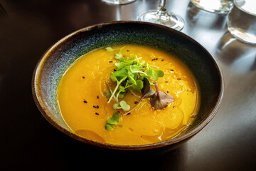 Microgreens on pumpkin soup at a vegan restaurant, elegant healthy dish, atmospheric food photo