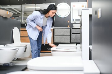 Young woman choosing bathroom toilet bowl and utensils for his home