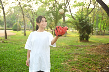 Smiling teenaged girl playing baseball in the park on a sunny spring day