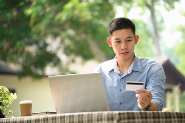 Young businessman using laptop making online payment with credit card at outdoor