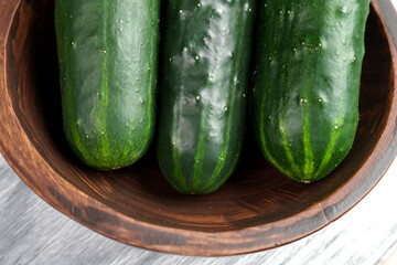 Fresh ripe whole green cucumbers in rustic wooden bowl. Healthy vegetable food