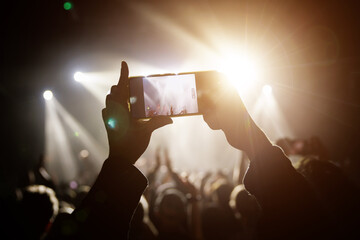 Capturing the electrifying atmosphere of a live music event, an audience member recording or taking...