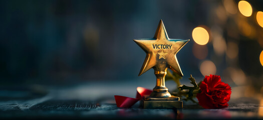 A gold star with the word victory written on it sits on a table with red flowers. Concept of accomplishment and triumph