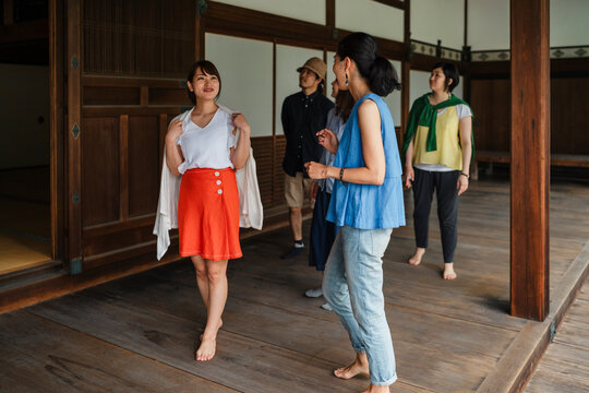 group of Japanese friends laugh and interact in a lively manner on the steps of a traditional wooden building