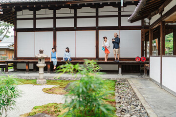 group of Japanese friends enjoy a casual visit to a traditional pavilion, with some walking and others taking photos
