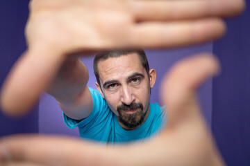 Young man doing frame using hands and fingers, isolated over purple background. High quality photo