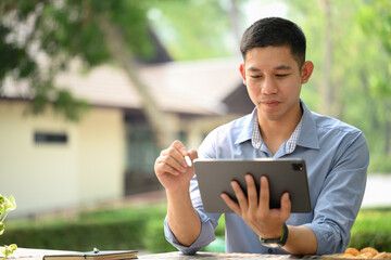 Handsome businessman using digital tablet at an outdoor table