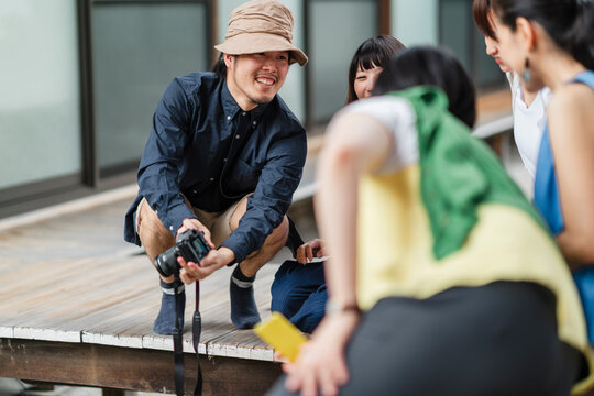A Japanese photographer interacts with his subjects during an outdoor photo session, exchanging smiles and capturing the cheerful essence of the moment