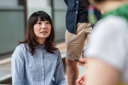 An intimate and earnest conversation outdoors, with a Japanese woman in a blue shirt speaking to her attentive friend.