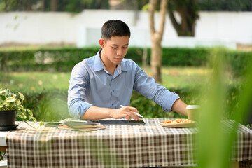 Young businessman working on digital tablet while sitting at table outdoors