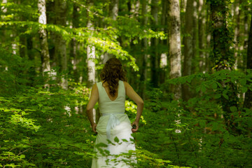 Naklejka premium Bride in white dress walking through the spring forest in La Fageda d en Jorda, La Garrotxa, Spain