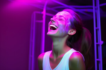 Portrait of a happy beautiful young woman with neon light on her face on a purple background.