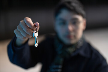 closeup of male hands holding keys to new house - real estate, housing and people concept