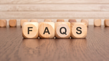 the text FAQS is written on wooden cubes on a brown background