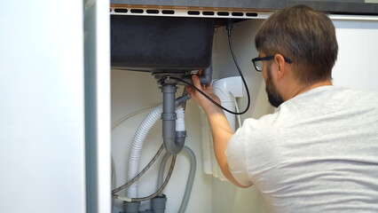Plumber repairs plumbing pipes in kitchen sink. Removing blockage clog in drain pipe. Replacement...