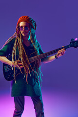 Young man with dreadlocks, beanie hat and sunglasses creating beautiful music, playing guitar...
