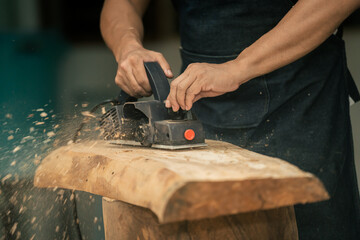 close up detail of hands and an electric hand planer