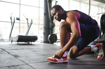 Sportsman tying shoelaces, ready for workout in gym, free space