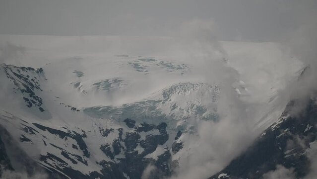 tranquil and calm Oldevatnet glacial lake in front of the melting Briksdalsbren glacier in Norway with snow capped mountains.