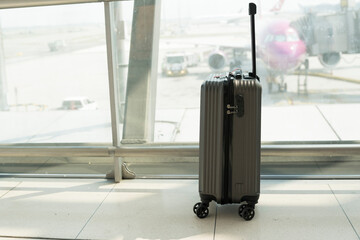 Suitcases in airport departure lounge and the airplane in background.Travel concept with hand...