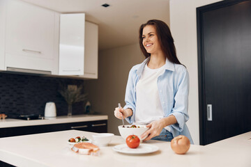 Woman preparing healthy salad with fresh vegetables in a modern kitchen interior concept