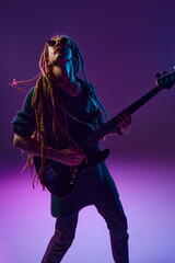 Passionate performer with dreadlocks pouring his heart out through his guitar playing against dark...