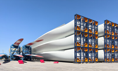 blades of wind turbines stack in a harbor and ready for shipping and assembling