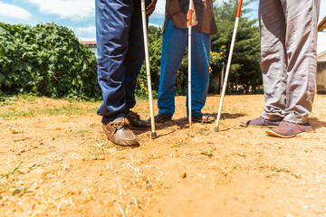 Close up of the feet of three blind people using the cane to walk