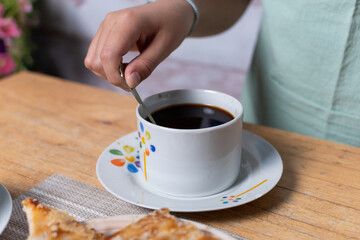 Stirring cup of freshly brewed coffee.