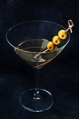 Martini. A glass of dirty martini cocktail with vermouth and olives, alcoholic beverage, on a black background