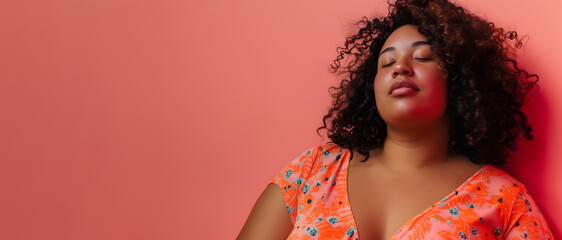 black woman in orange dress with eyes closed against a pink background, body positive concept