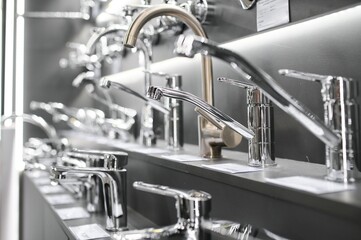 Water taps of different types and shapes on the counter in the store. Retail trade in sanitary ware. Foreground. - obrazy, fototapety, plakaty