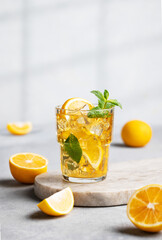 Iced drink with lemon, mint in a glass on a marble board on a light background with shadow and...