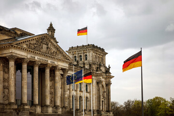 The German flag waves at the Bundestag, the building of the German parliament. Cloudy sky.