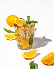 Iced tea with lemon and mint on white background with a shadow and citrus fruits.