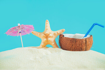 Coconut with a straw, shells, starfish and a sun umbrella on the sand. - 779665106