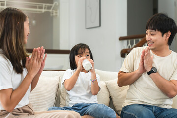 Happy Asian family, mother and father clapping hands cheering their little 6 year old daughter...