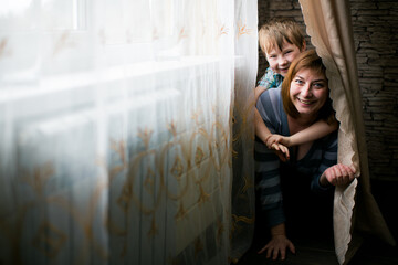 Happy mom and her toddler playing in a cozy room. - 779665553