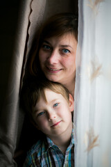 Portrait of a woman with her young son playing in the room. - 779665594
