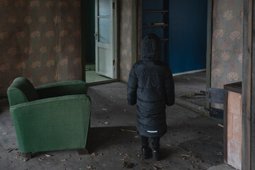 A child in a black coat entered an abandoned house.