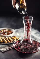 Red wine is poured from a bottle into a carafe on a table on which there is venison, Hungarian or...