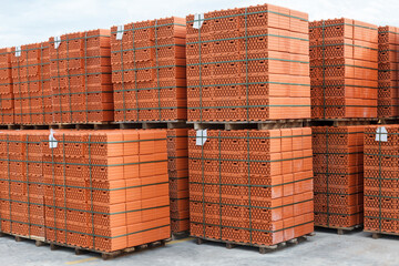 Stacks of new, red ceramic brick stacked on wooden pallets.
