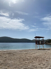 Fototapeta na wymiar Silhouette of lifeguard tower on the pebble beach. Calm beach in the morning