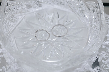 White gold rings lie in a crystal plate in close-up