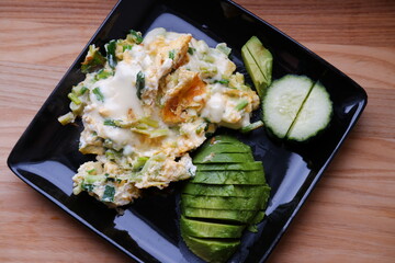 ceramic plate with fried egg, onion, cheese, ripe avocado, fresh cucumber. healthy breakfast. delicious healthy food