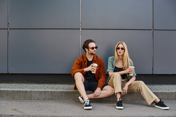 couple engaged in a romantic moment, sitting on the curb with coffee © LIGHTFIELD STUDIOS
