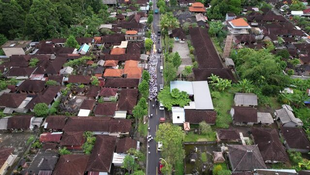 The celebration parade took up half of village road, with cars squeezing in on right. White from festive clothes, crowd moves slowly to sea, gathering more and more residents. Aerial view of Melis day